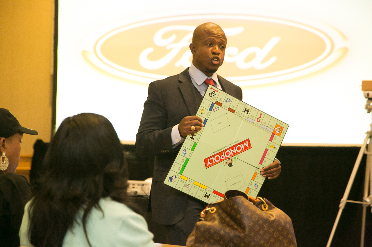 Dr. Karim R. Ellis speaking at a Ford Motor Company leadership event with the Ford logo and audience visible